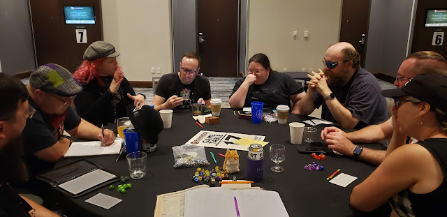 Photo from DM's view of players at reapercon table in convention center hallway. My hamster plush sits prominently in the middle of the table next to my beer and notebook