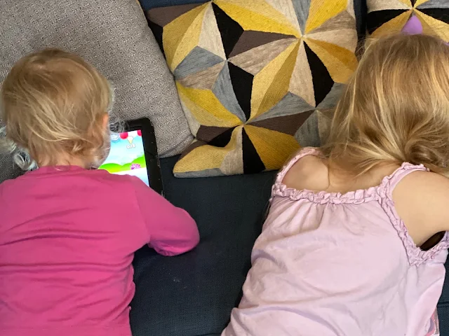 The back of my daughters' heads as they play on an ipad and iphone in their PJ's 