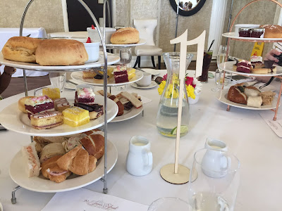 an afternoon tea spread including cakes, scones and sandwiches