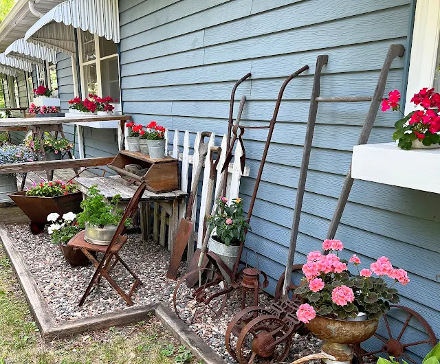 Photo of junk garden plantings and decor along the house.