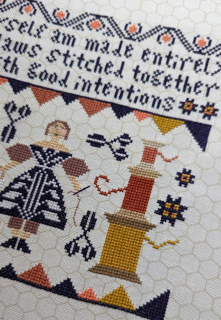 Good Intentions by Kathy Barrick cross stitch, words read I myself am made entirely of flaws stitched together with good intentions, a lady holding an embroidery hoop and needle. There are scissor and star motifs and stacks of thread spools.