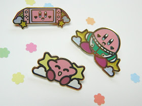 A photo showing three enamel pins of Kirby by Nintendo, they are made by artist Illustrator Jake