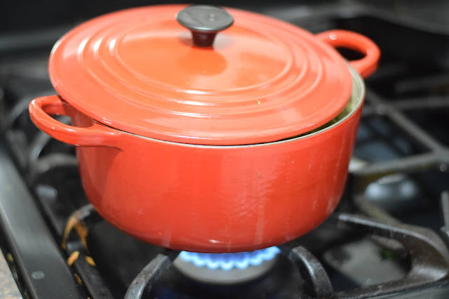 The vegan pozole verde recipe simmering in a red pot on the stove.