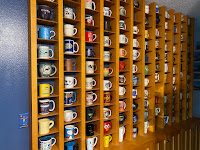 A shelving unit holding over 100 mugs, each displayed in its own cubicle.