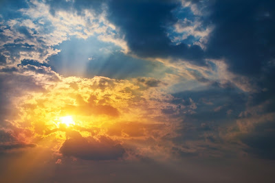 Hermoso amanecer con el sol resplandeciente y nuebes de colores en el cielo azul