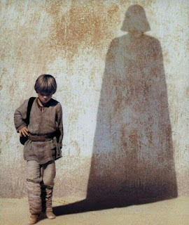 El niño Anakin Skywalker andando con una sombra en la pared mostrando la forma de Darth Vader