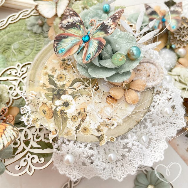 Mixed media canvas created with Tim Holtz Distress sprays; Prima Marketing In the Moment Collection flowers and ephemera; and Reneabouquets butterflies, chipboard, lace, glitter glass and pearls.