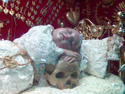 El Santo Niño de las Suertes recostado sobre la calavera.