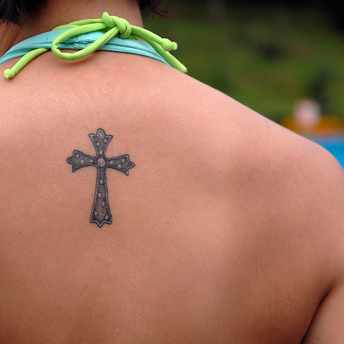 Girl with rosario cross tattoo on her upper back and girl with small cross