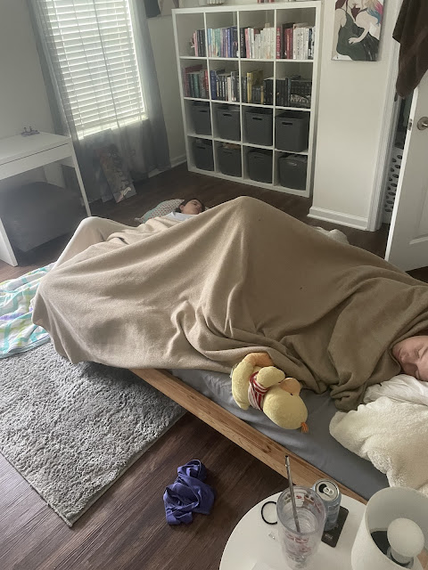 You and your sister asleep in her room. You are sleeping on the floor in front of her bed on her gray carpet. She is asleep in her bed facing the doorway.