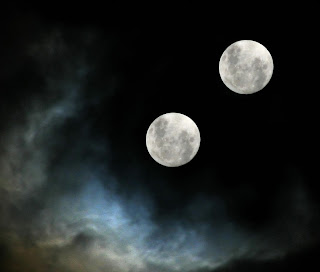 Imagen de una noche nublosa en la se puede ver entre las nubes dos lunas llenas
