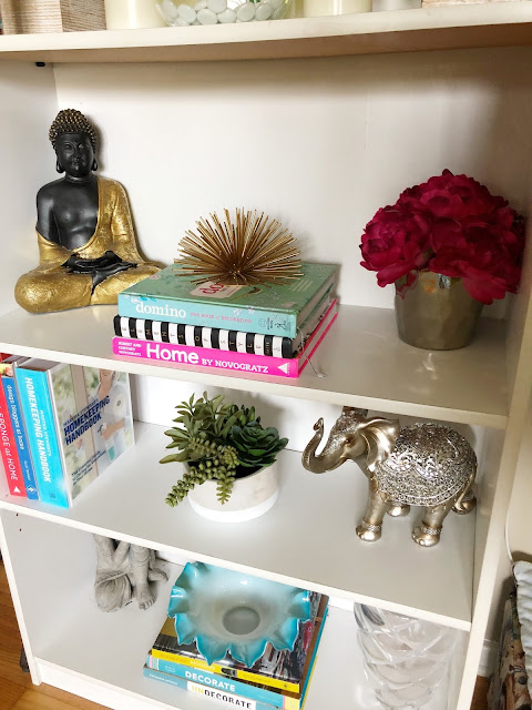 an organized and styled bookshelf with books and decor items