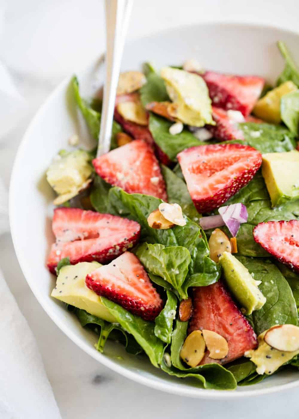 Strawberry Spinach Salad - A light and refreshing salad filled with fresh strawberries, almonds, feta and greens. Top with poppy seed dressing to make the perfect summer salad recipe! 