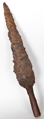 A long pointed iron spearhead, which looks bumpy now due to corrosion before it was excavated