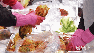 Children and adults rubbing red pepper paste into salted napa cabbage