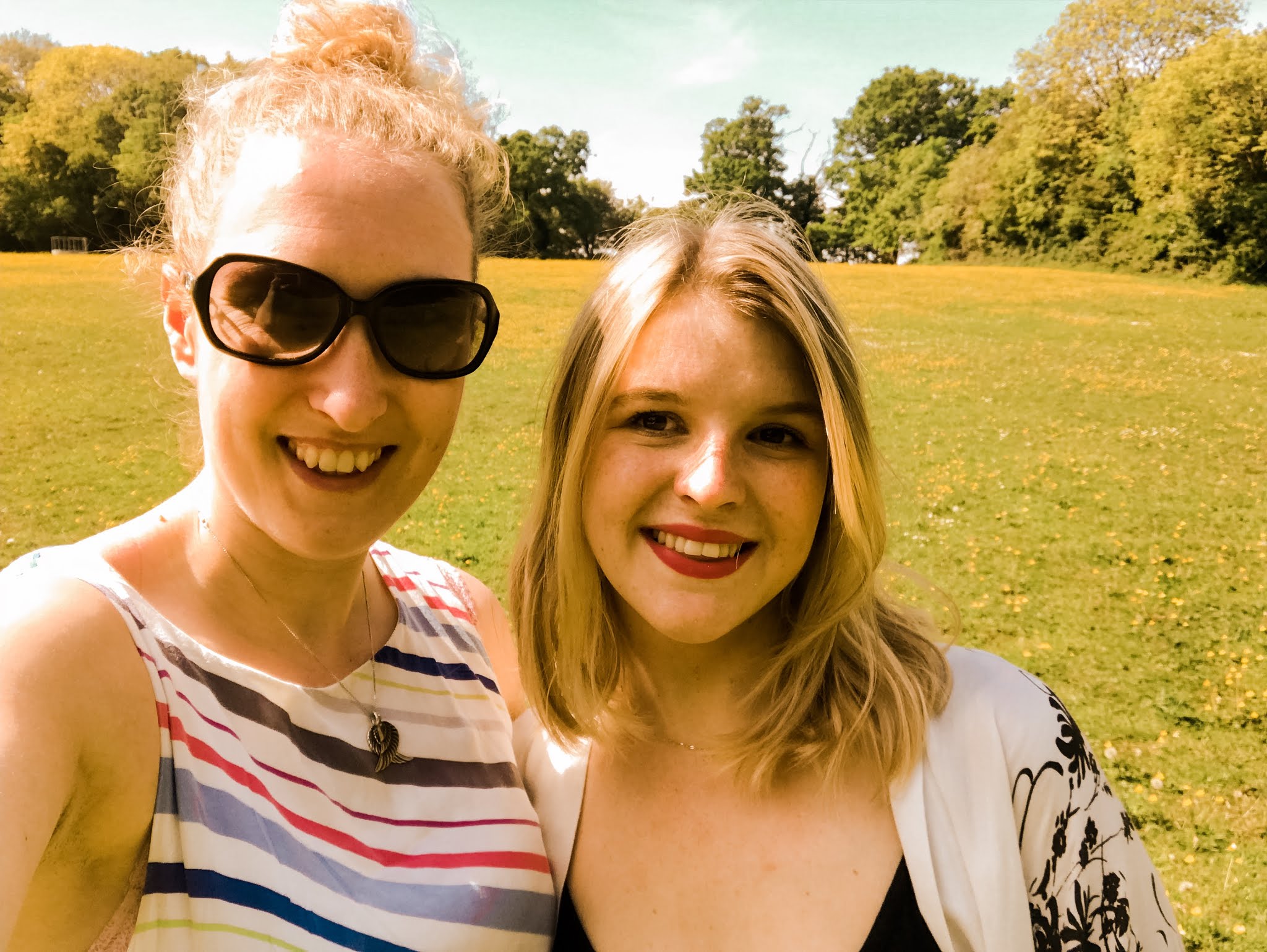 Two friends smiling in a field during Summer 2019