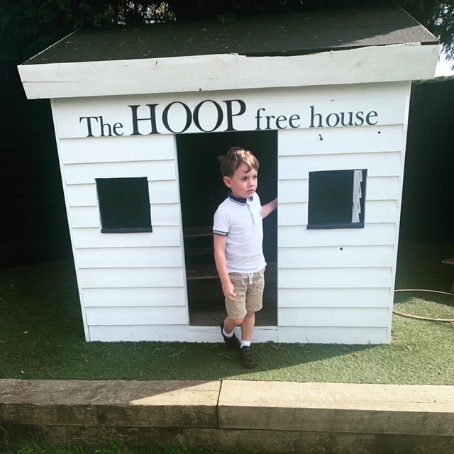 Boy coming out of a white wooden wendy house