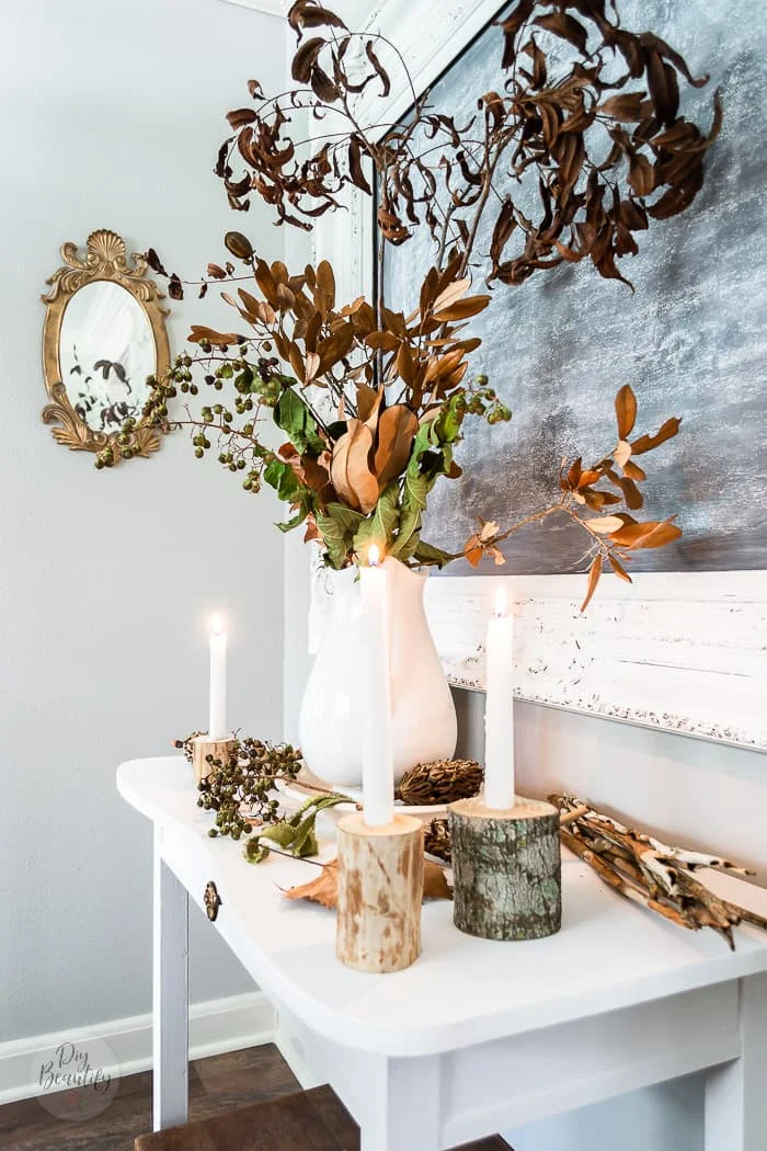 gold mirror, side table with Fall foraged berries, branches, seed pods and candles plus ironstone pitcher filled with real fall dried leaves