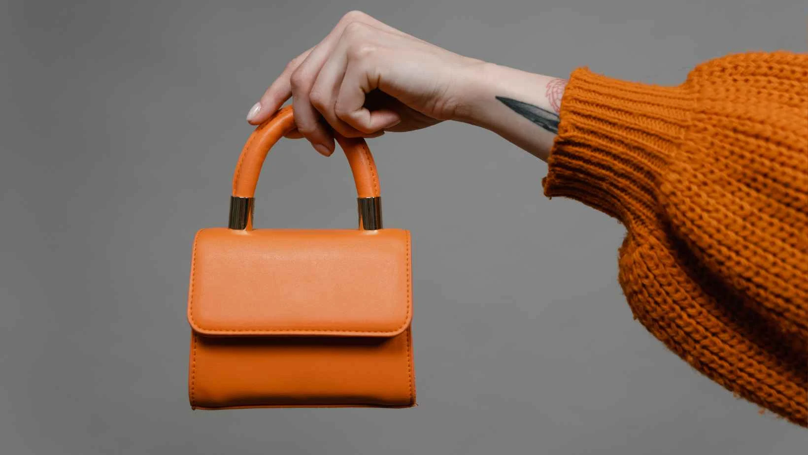 A image of an arm holding an orange handbag stock image from canva pro