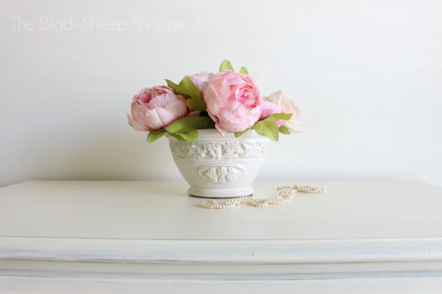 Peonies in vase on top of dresser.