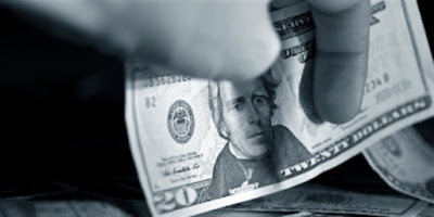 o mână care se pune să ia... o bancnotă de 20 de dolari - imagine preluată de pe christianheadlines.com