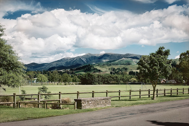 A view of Mt Oxford across playing fields. Blue sky, white fluffy clouds.