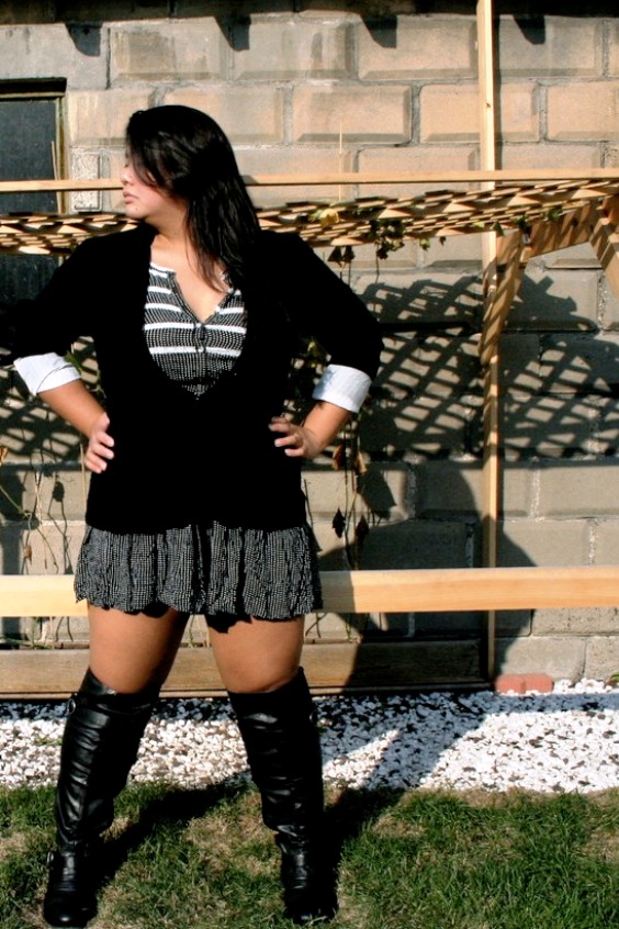 Woman wearing a gray mini skirt, tights and black knee high boots