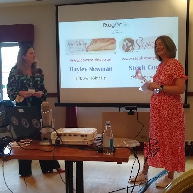 Hayley and Steph standing in front of a screen with their presentation on