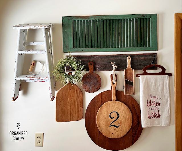 Photo of a farmhouse kitchen wall with cutting boards, a shutter, and a stepstool.