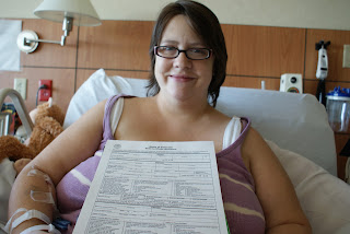 amanda the mom holds eliza the baby's birth certificate worksheet while sitting in her hospital bed with an iv port in her arm