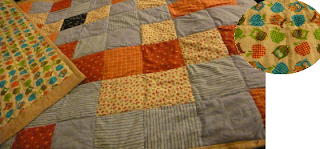 photo of the final quilt, the top corner is turned over to show the reversible underside which is a pattern of owls and apples.