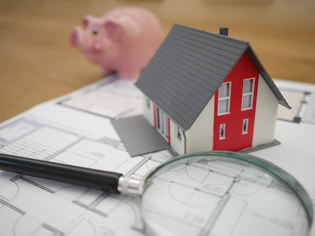 A model of a house which is kept on drawings sheets with magnifying glass 