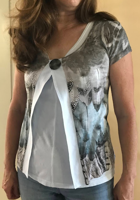 Picture of completed refashioned top made into a lightweight jacket. Top print of feathers with colors of white, gray and black and silver embelishments.