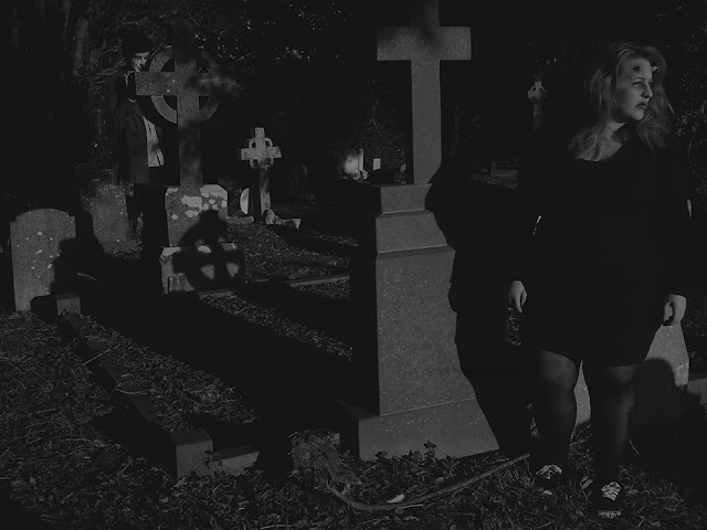 Horned woman being stalked by a creepy man in a cemetery 