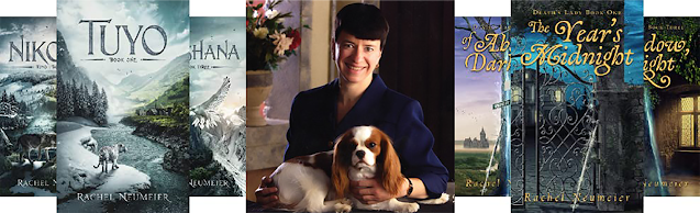 Rachel Neumeier with Cavalier King Charles Spaniel and two 3-book series from her prolific collection: The “Tuyo” series and the “Death’s Lady” series.