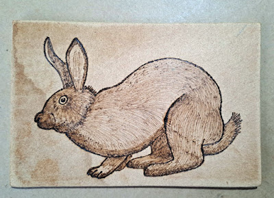 a drawing of a rabbit on a piece of wood created with a wood burner