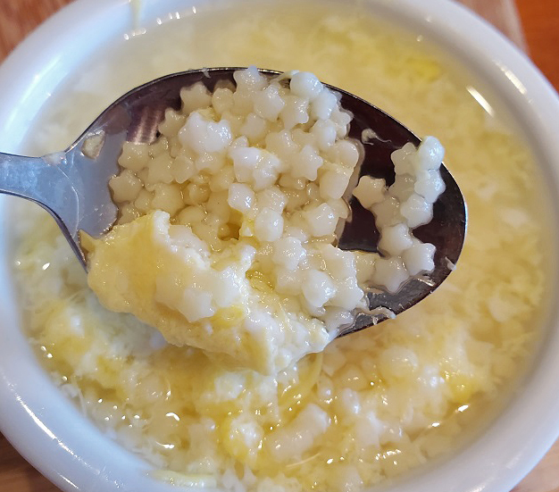 tiny pasta called pastina in a white bowl with cooked eggs in a broth