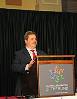 Scott LaBarre in a suit speaking at a podium