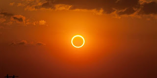 No dia 21 de junho de 2020, acontece o primeiro eclipse solar anular do ano. O aguardado fenômeno não poderá ser visto a olho nu no Brasil, mas existe a possibilidade de assisti-lo ao vivo pela internet.  O eclipse anular, consiste em um tipo de eclipse parcial, no qual a Lua não consegue cobrir totalmente o Sol, ao passar entre ele e a Terra. Dessa forma, é possível ver as bordas do astro brilhar atrás da Lua.  Conforme o Space.com, o evento será visível em várias regiões da Ásia e da África. Quem estiver na Índia, Paquistão, Arábia Saudita, República Democrática do Congo, Etiópia, Omã, Iêmen, Taiwan, Etiópia e Sudão, entre outros países, terá boa visibilidade do fenômeno, assim como no norte da Austrália e na porção norte do Oceano Pacífico.  Descrição: Foto de um céu alaranjado com poucas nuvens. Ao centro, um anel brilhante de fogo. Ao redor, um clarão dourado irradia os tons em degradée do amarelo, laranja e vermelho.