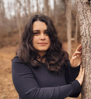 Headshot of Sara. She has medium-length dark brown hair and wears a black long-sleeved shirt