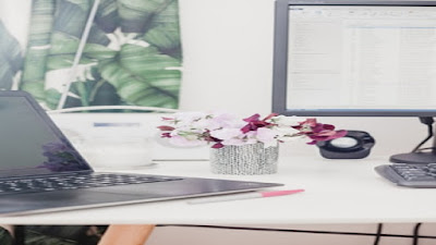 Affiliate marketing work station with working tools, computer, Tv screen, flowers and calculator.