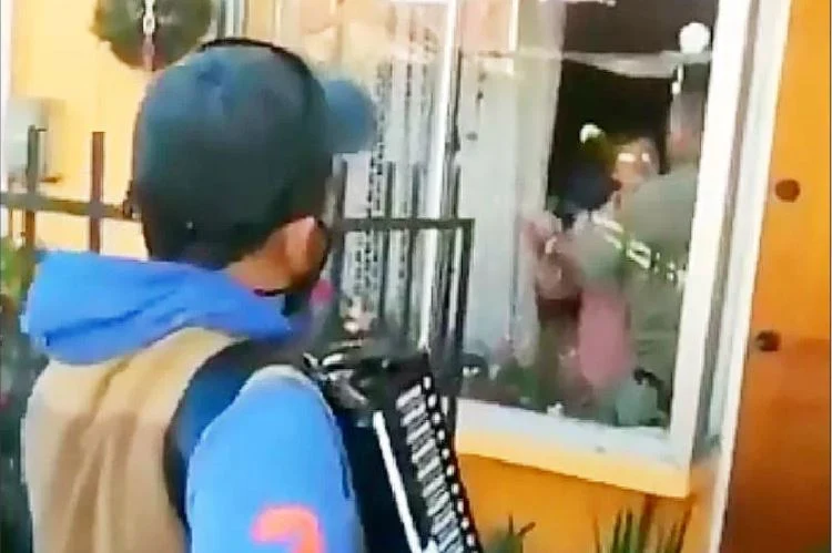 Hijo toca el acordeón para sus padres desde la ventana