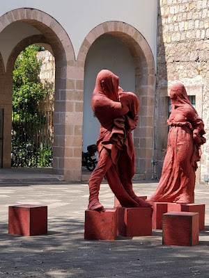 red sculpture of a male and female standing on boxes with boxes around them