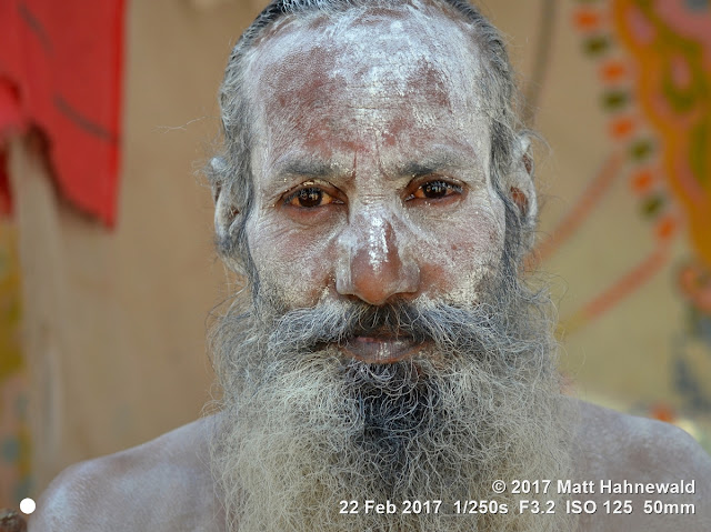 matt hahnewald photography; facing the world; picture; photography; photo; image; illustrative editorial; natural frame; backdrop; face perception; physiognomy; nikon d3100; nikkor af-s 50mm f/1.8g; prime lens; 50mm lens; 4x3 aspect ratio; horizontal format; street; portrait; closeup; head shot; full-face view; white; outdoors; color; character; real people; human head; high forehead; receding hairline; face; painted face; sacred ash; vibhuti; bloodshot eyes; facial expression; eye contact; full beard; barechested; bareheaded; consent; spiritual; religious; hinduism; mela; celebration; devotee; worshiper; pilgrim; traditional; cultural; shivratri mela; bhavnath; junagadh; gujarat; asian; indian; one person; male; adult; middle-aged man; posing; authentic