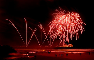 Red Fireworks on Blackpool Beach at night time.