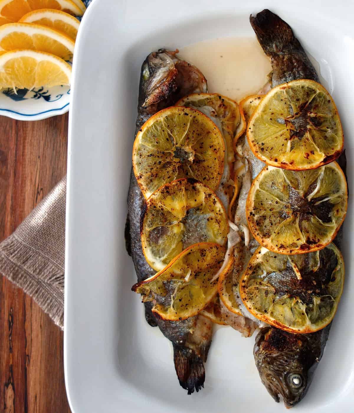 Baked Whole Rainbow Trout with Shallots, Herbs, and Jalapeño on a white serving plate.