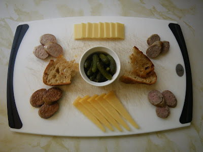 A charcuterie platter featuring homemade weisswurst, kielbasa, duck sausage, and merguez with Sylvan Star cheese