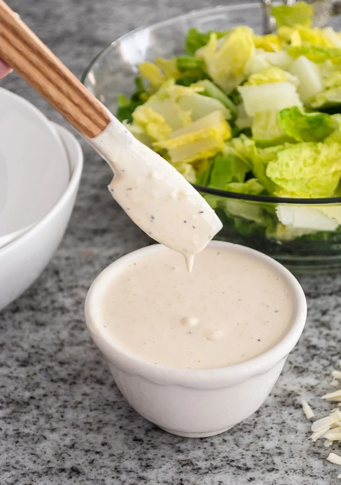Caesar salad dressing in bowl, romaine lettuce
