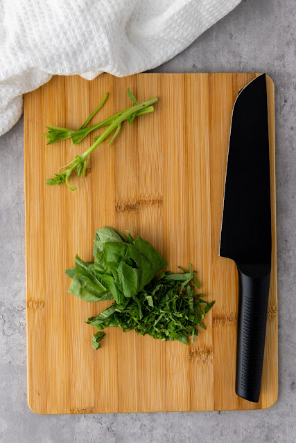 basil being chopped on a cutting board.