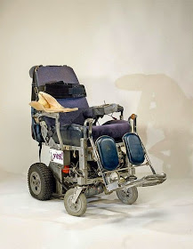 Old-style electric wheelchair, well worn.